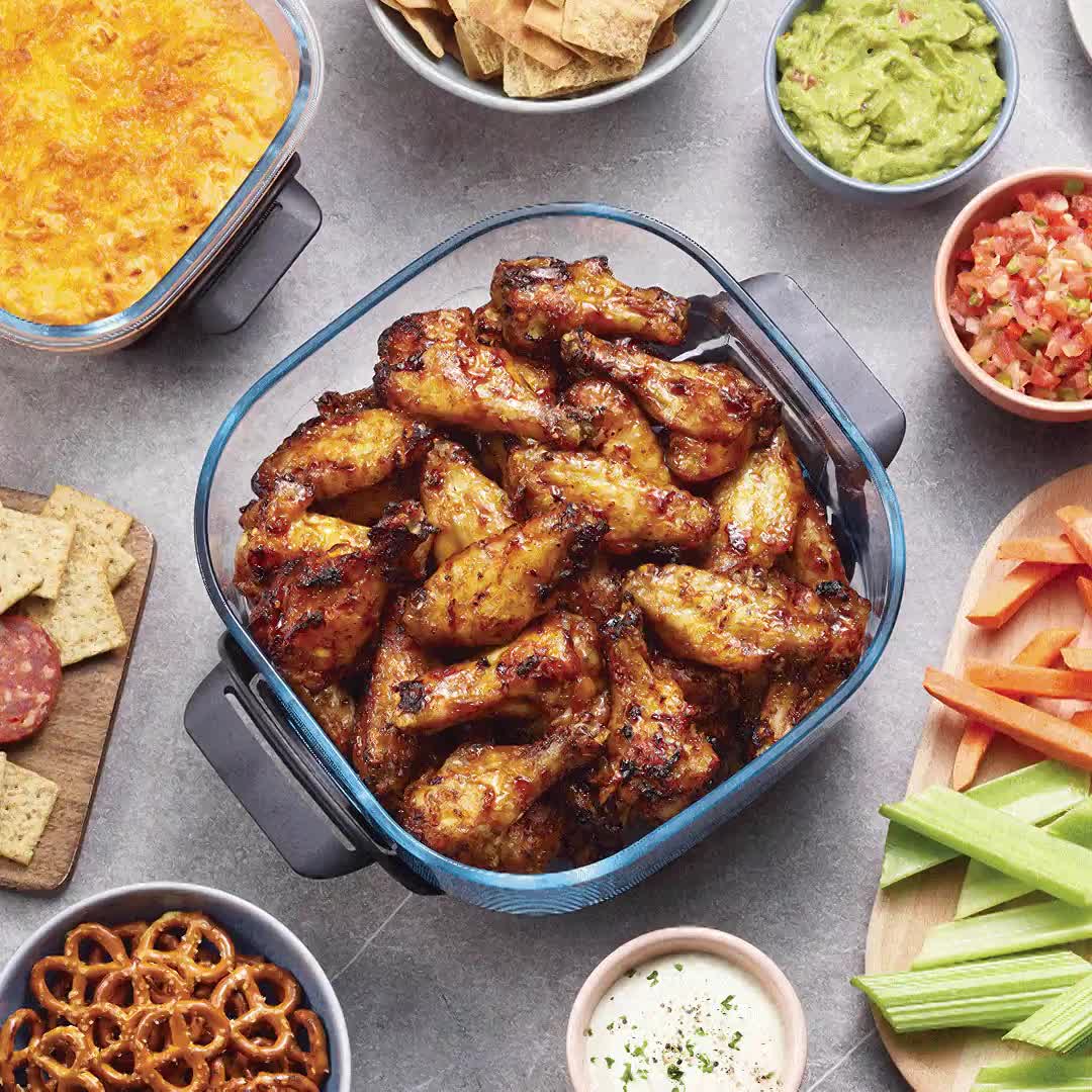 Contenedor de vidrio del Ninja Crispi lleno de alitas, usado directamente como bandeja para servir junto a otros snacks